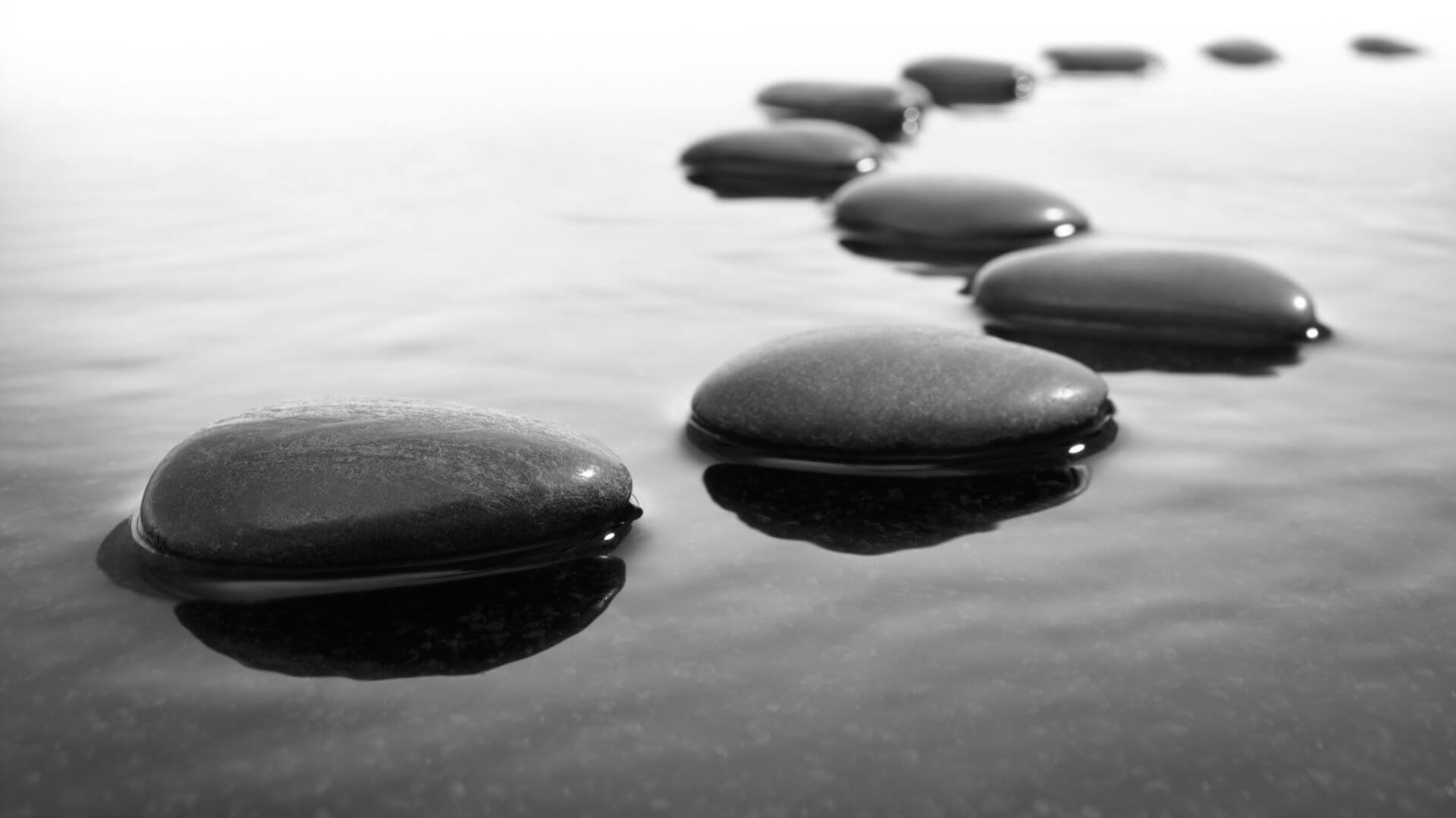 Foto em preto e branco de pedras formando um caminho sobre as águas